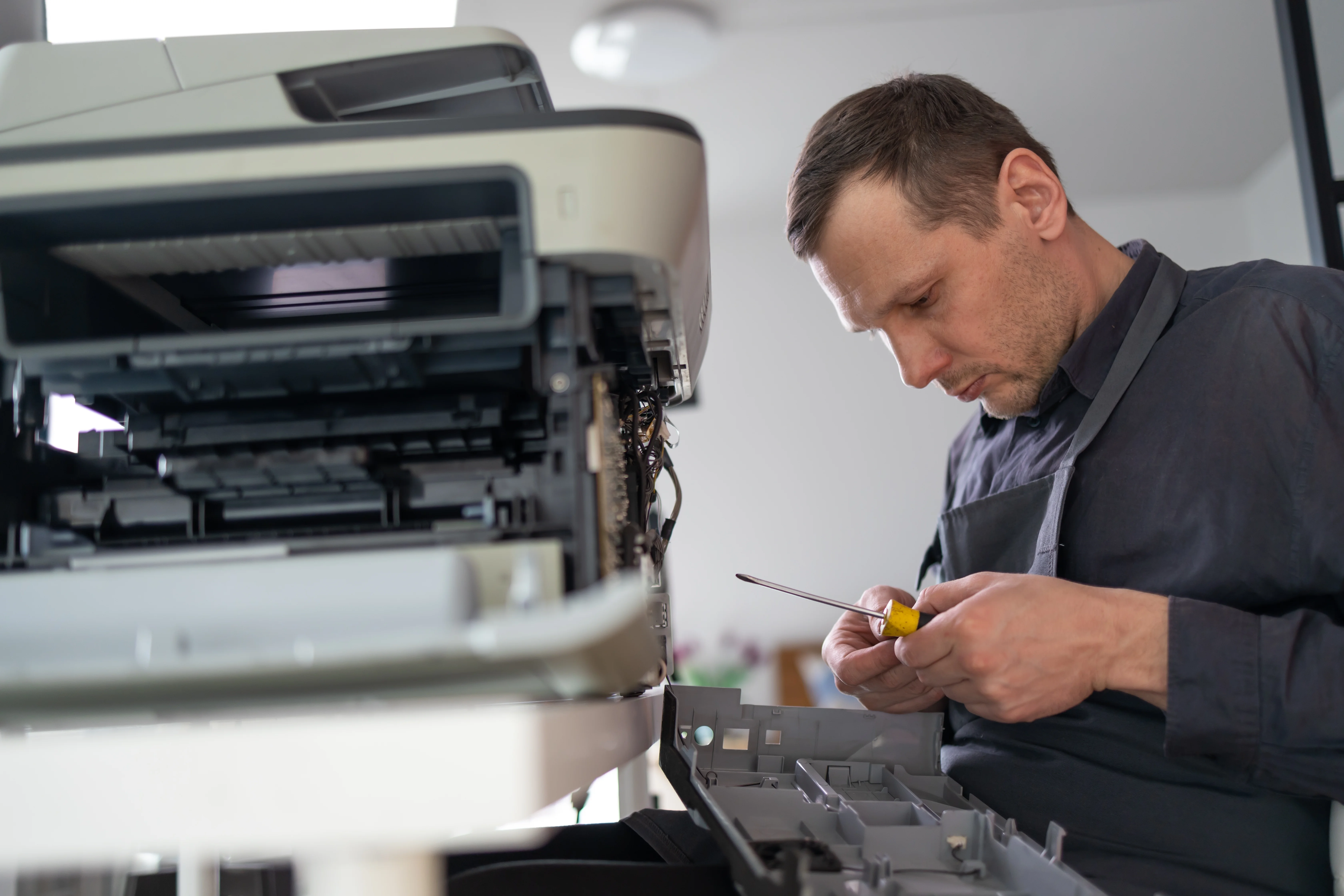 Técnico SEIM reparando impresora con herramientas profesionales